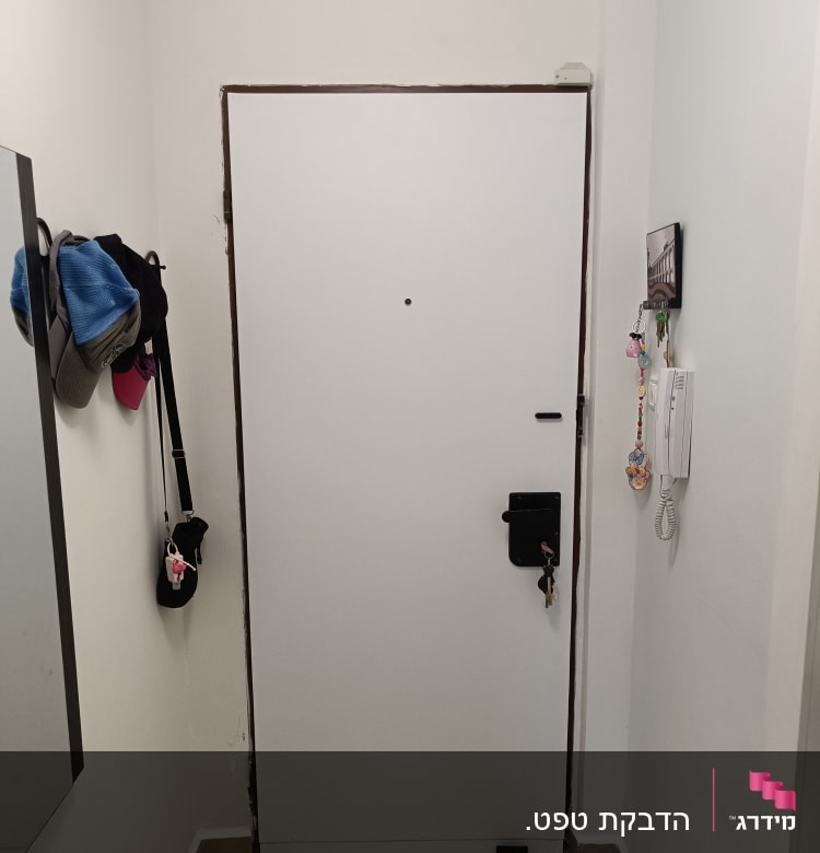 דלת לבנה עם מסגרת חומה, מנעול ומפתחות תלויים